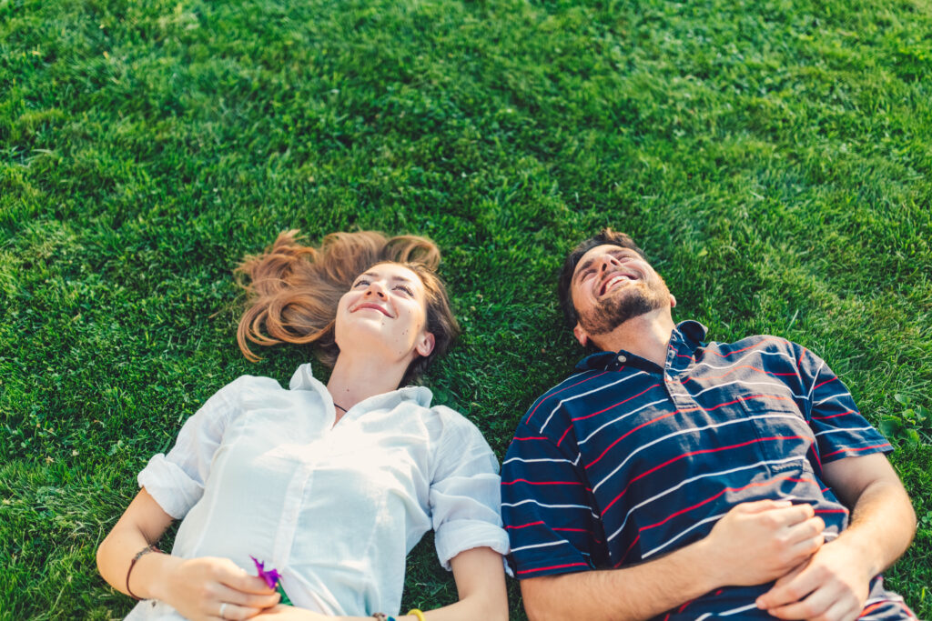 man and woman laying in the green grass